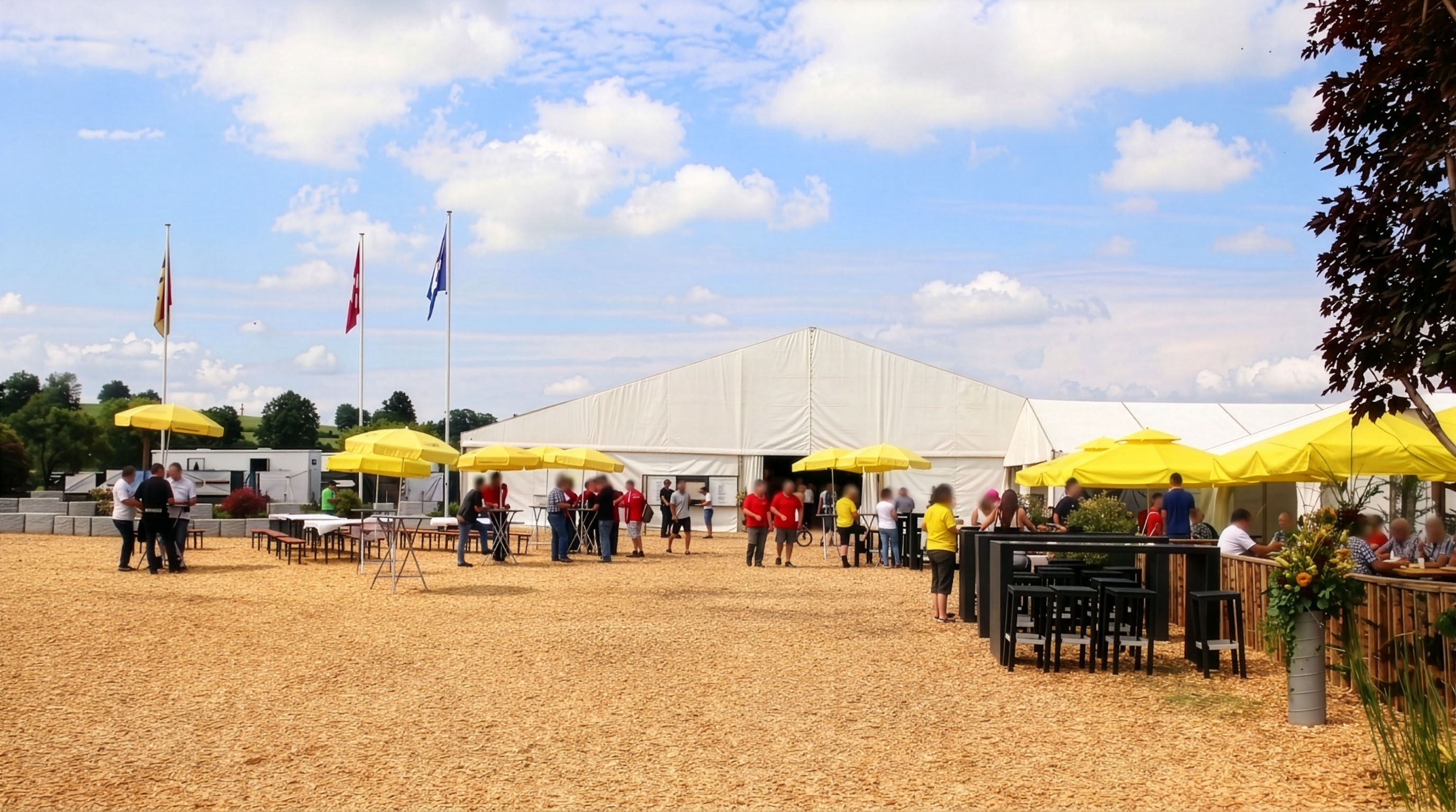 Festplatz-Panorama mit weissem Festzelt, Fahnenmasten, gelben Schirmen und Bartischen mit Sonnenblumen-Deko
